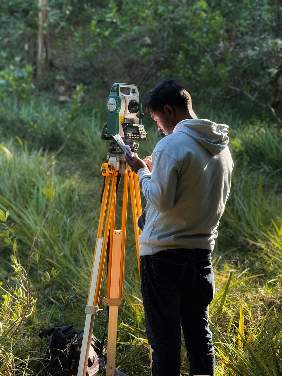 Arazide total station cihazıyla ölçüm yapan uzman; temsili stok fotoğraf